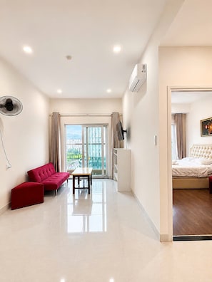 A modern hotel room with a large bed, a seating area with a red sofa and a table, and a view through the window. - Mermaid Seaview-Apartment near beach (Vũng Tàu)