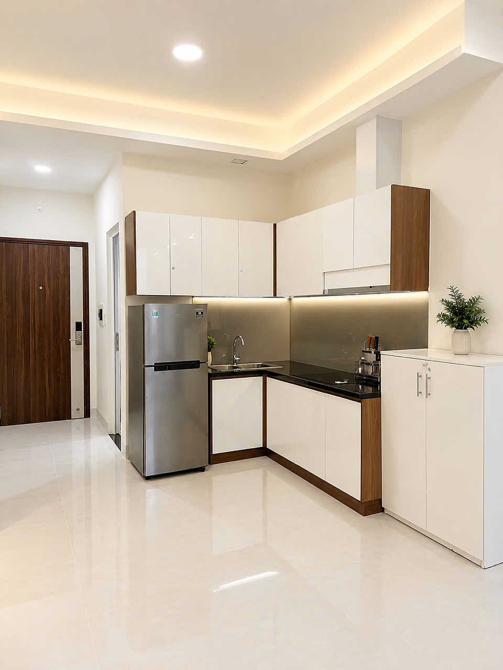 Una cocina moderna con armarios blancos, un refrigerador de acero inoxidable y una encimera negra.