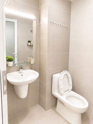 A bathroom with a white sink, a toilet, and a glass shower enclosure. - Mermaid Seaview-Apartment near beach (Vũng Tàu)
