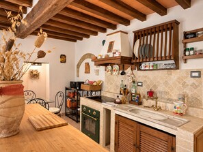 Una cocina con encimera de madera, horno empotrado y un tendedero para platos.