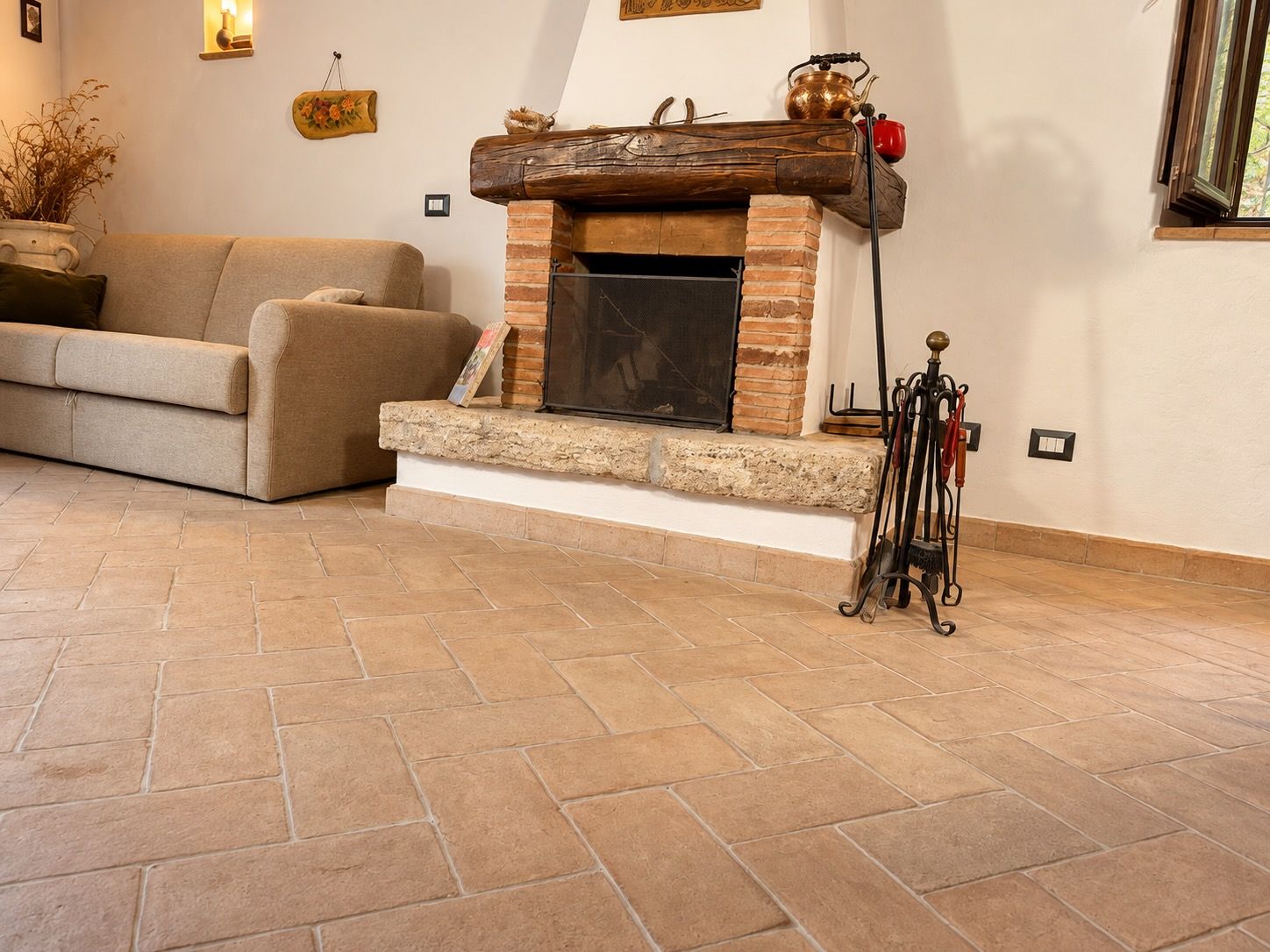 A living room with a fireplace, a sofa, and a stone-tiled floor.