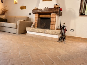 A living room with a fireplace, a sofa, and a stone-tiled floor.