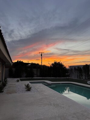 A residential backyard with a swimming pool, a patio, and a view of the sunset. -     Resort-Style Desert Oasis + Pool & Spa (Bermuda Dunes)