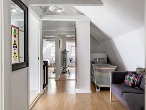 A spacious living area with a sofa, a colorful cushion, a baby playpen, and a large mirror. - Guttamåla by Interhome (Tving)