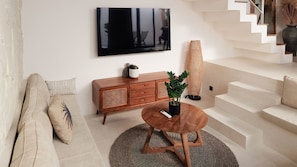 A modern living room with a sofa, a wooden cabinet, a round coffee table, and a staircase. - Enso Resort (Tabanan)