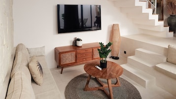 A modern living room with a sofa, a wooden cabinet, a round coffee table, and a staircase.