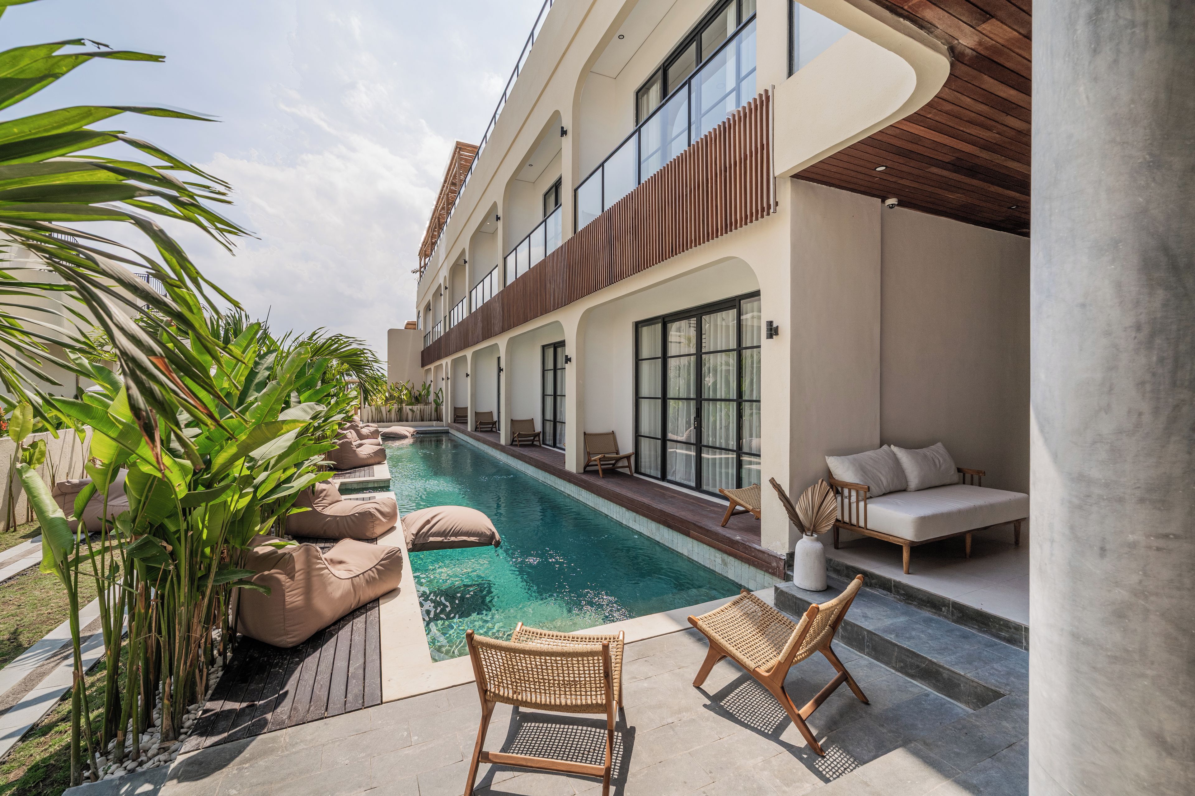 Un hôtel moderne doté d’une piscine, d’un espace extérieur aménagé et de plantes tropicales.