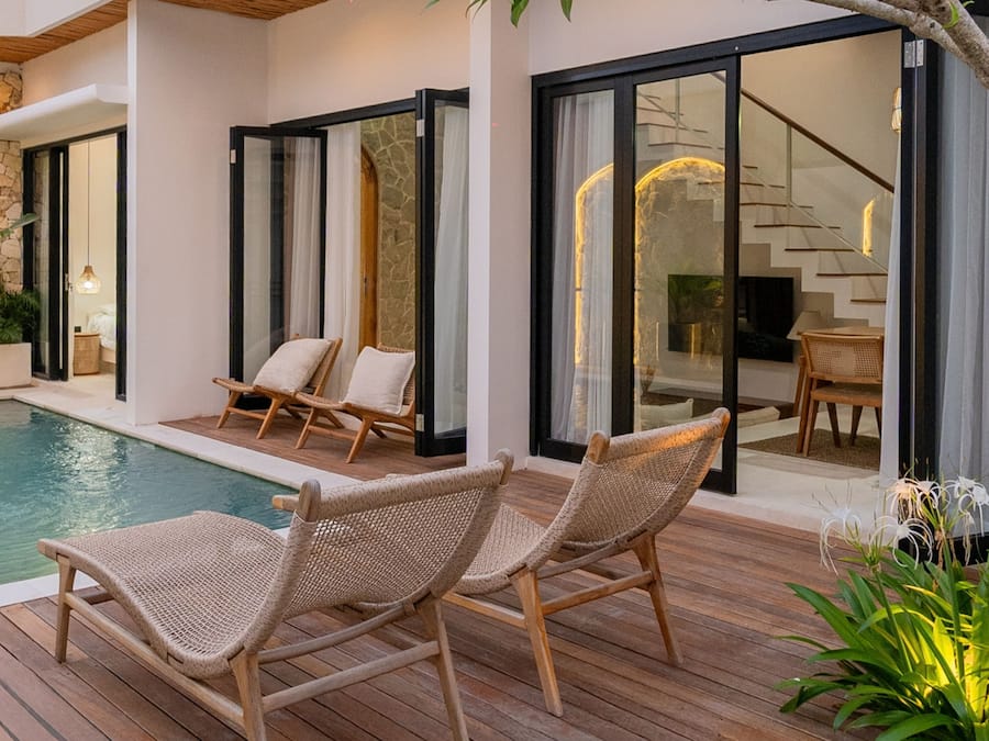 Un área junto a la piscina con sillas de mimbre y una terraza de madera.