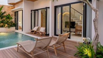 A poolside area with wicker chairs and a wooden deck.