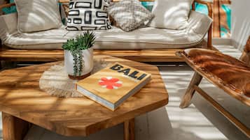 A wooden coffee table with a book titled 'BALI' and a potted plant.