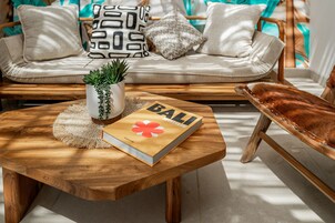 A wooden coffee table with a book titled 'BALI' and a potted plant.