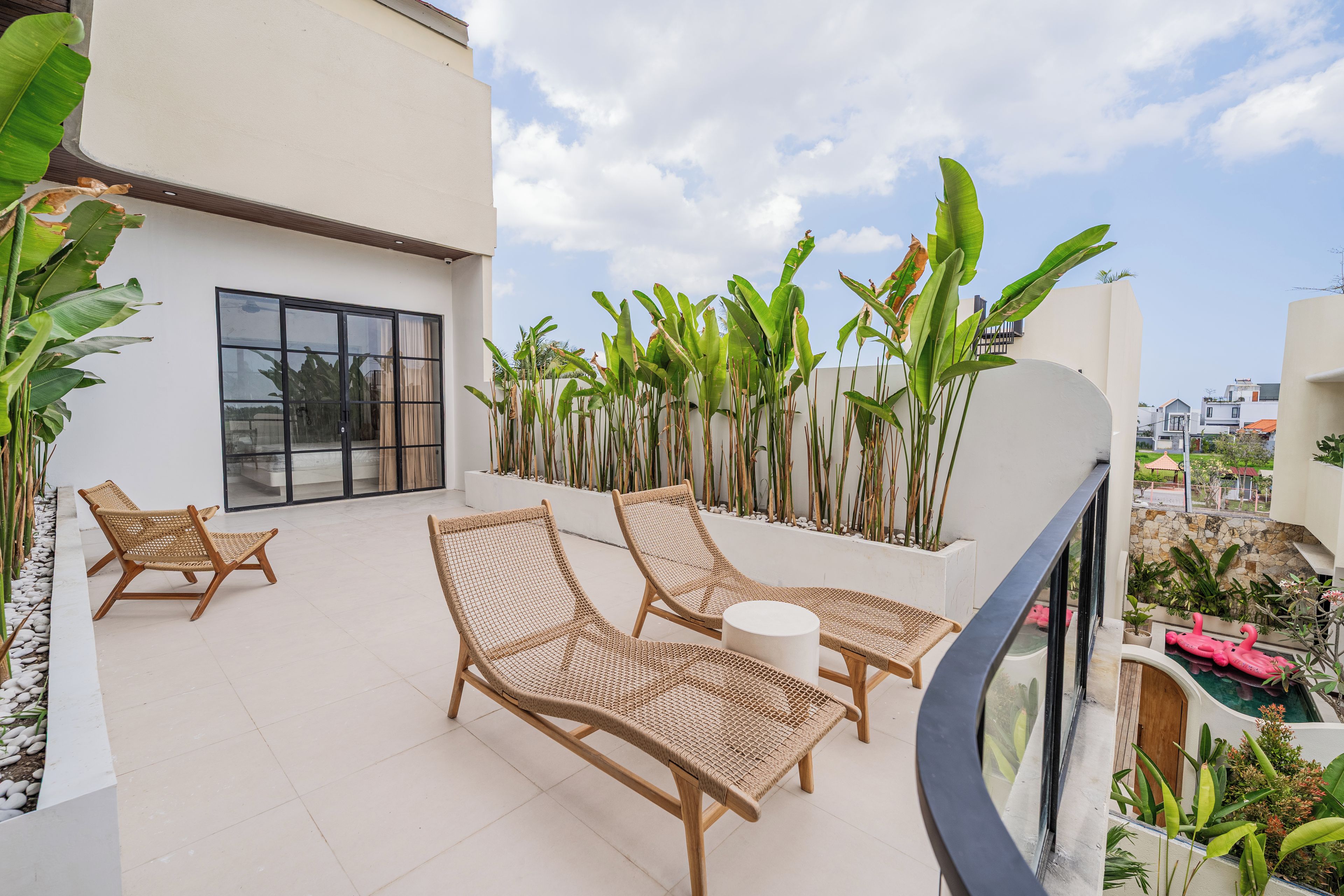 Un balcone con poltrone in vimini, un tavolino rotondo e vista su una zona residenziale.
