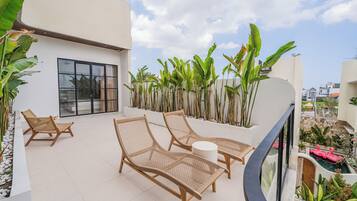 Un balcone con poltrone in vimini, un tavolino rotondo e vista su una zona residenziale.