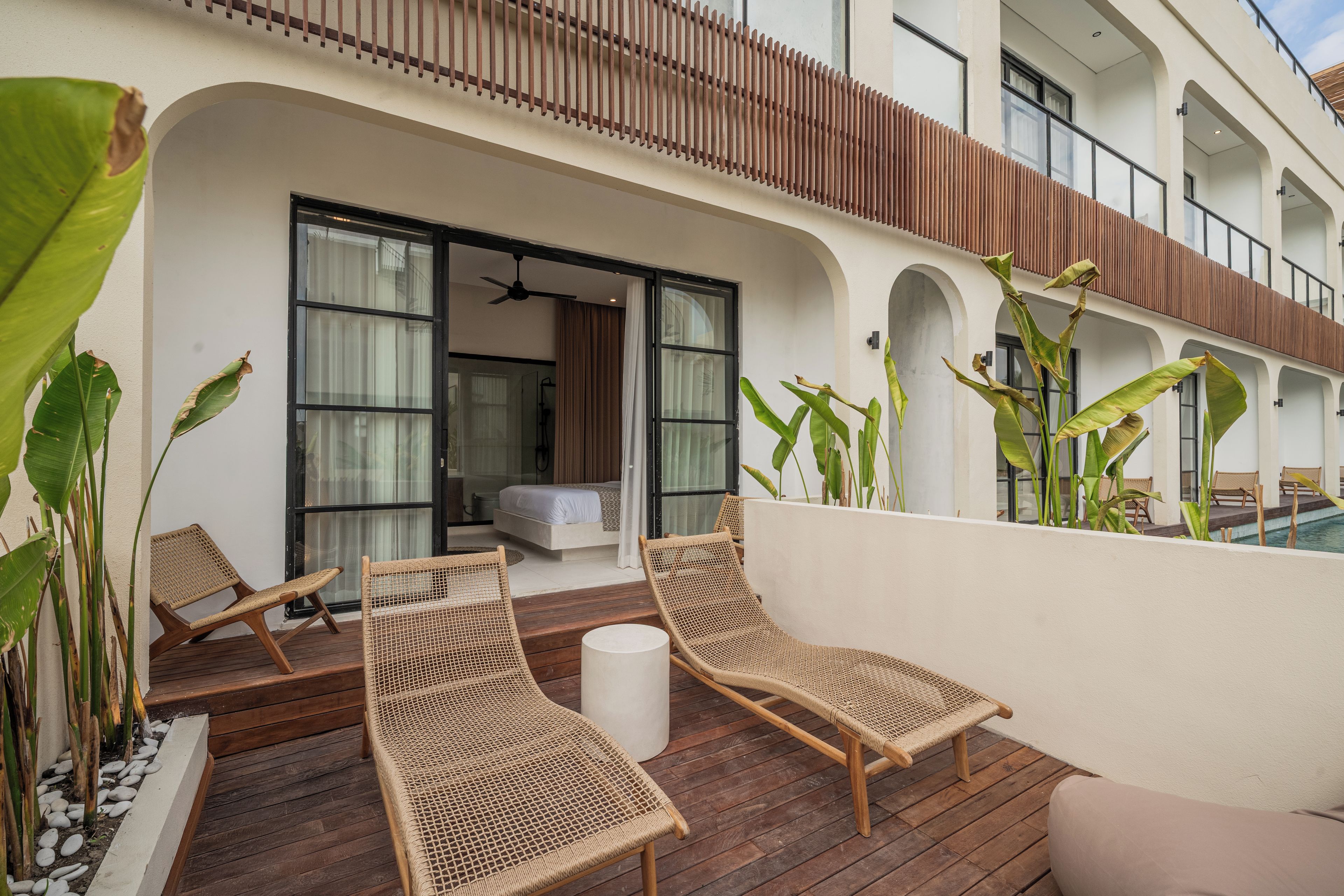 A balcony with wicker furniture, a bed, and a view of the pool.