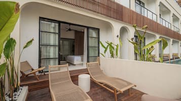 A balcony with wicker furniture, a bed, and a view of the pool.