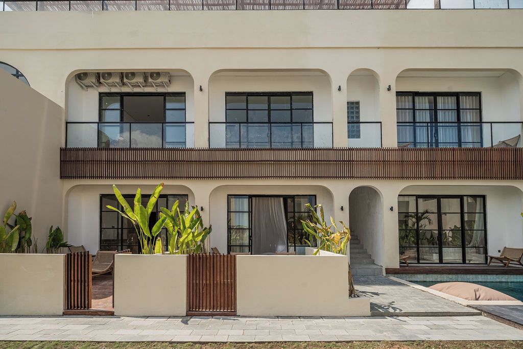 Un bâtiment à deux étages doté d’une piscine, d’un espace extérieur aménagé et de grandes fenêtres.