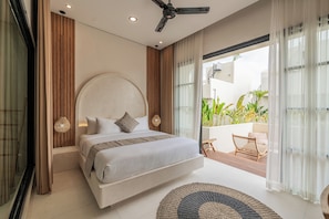 A modern bedroom with a large bed, a ceiling fan, and a view of a balcony with plants. - Enso Resort (Tabanan)