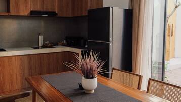 Una cucina moderna con mobili in legno, un frigorifero nero e un tavolo da pranzo con un sottopiattino intrecciato.