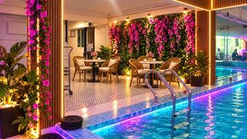 Un espace aménagé au bord de la piscine, avec des sièges et un mur recouvert de fleurs.