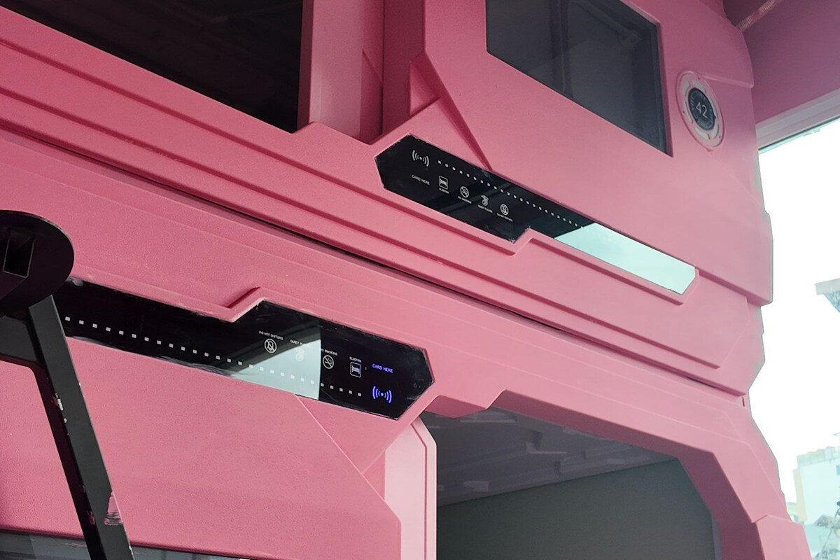 Una habitación rosa con un ventanal grande, un panel de control y una escalera.