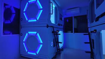 Une pièce dont les murs sont ornés d’un motif circulaire illuminé de lumière bleue, avec un panneau de contrôle et une fenêtre.
