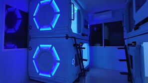 A room with a blue-lit circular design on the walls, a control panel, and a window.