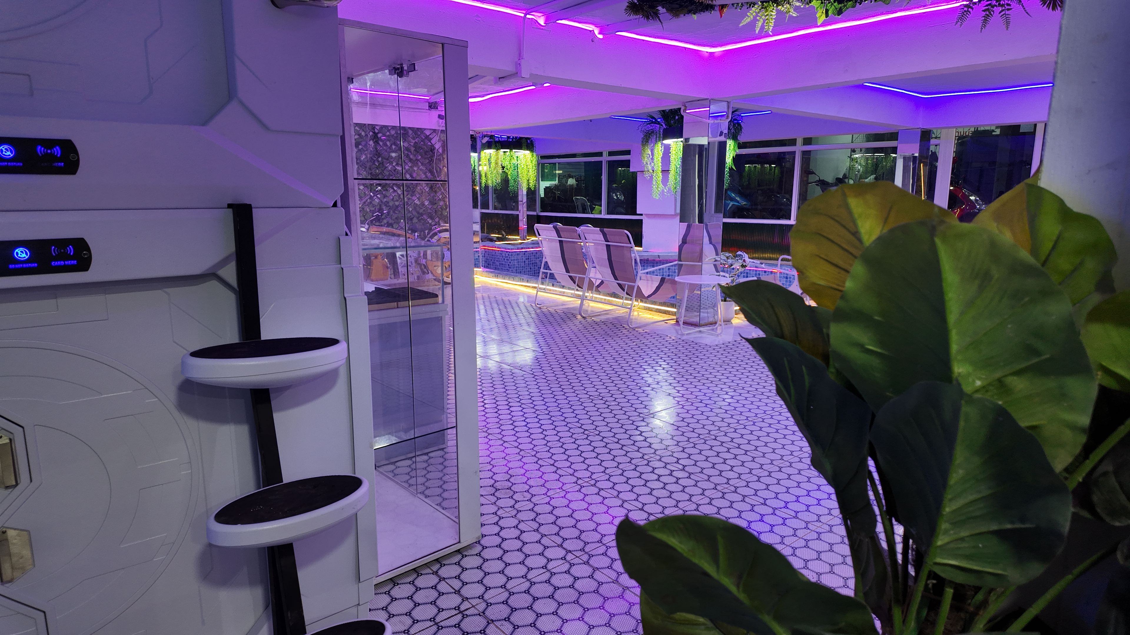 Un interior moderno con suelo hexagonal, una zona de estar con sillas y una mesa, y un separador de vidrio.