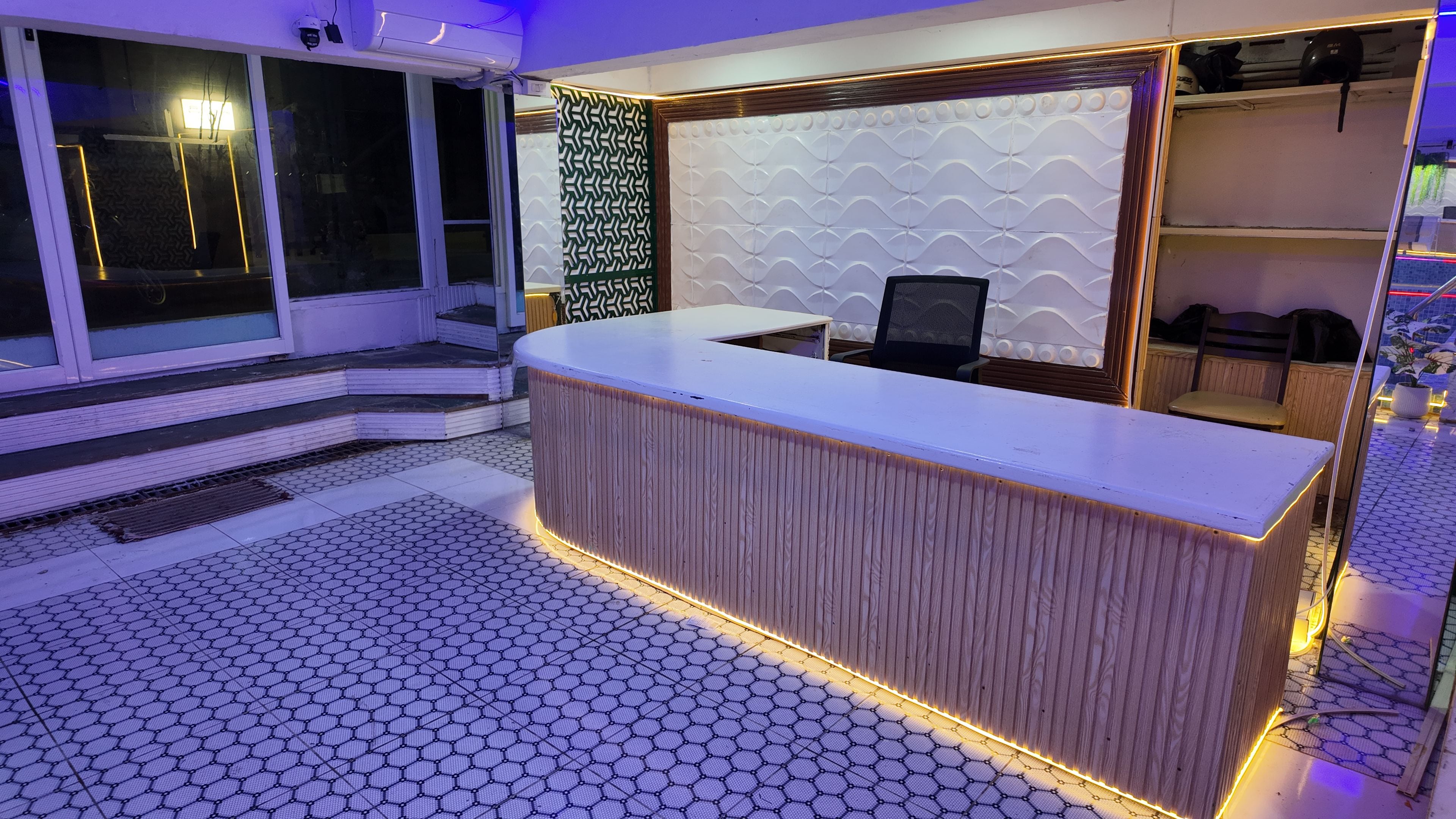 A reception desk with a modern design, a patterned wall, and a seating area with chairs.