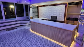 A reception desk with a modern design, a patterned wall, and a seating area with chairs.