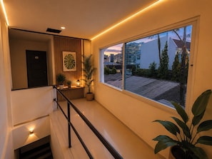 Un interior moderno con una escalera, un ventanal grande y plantas en macetas.