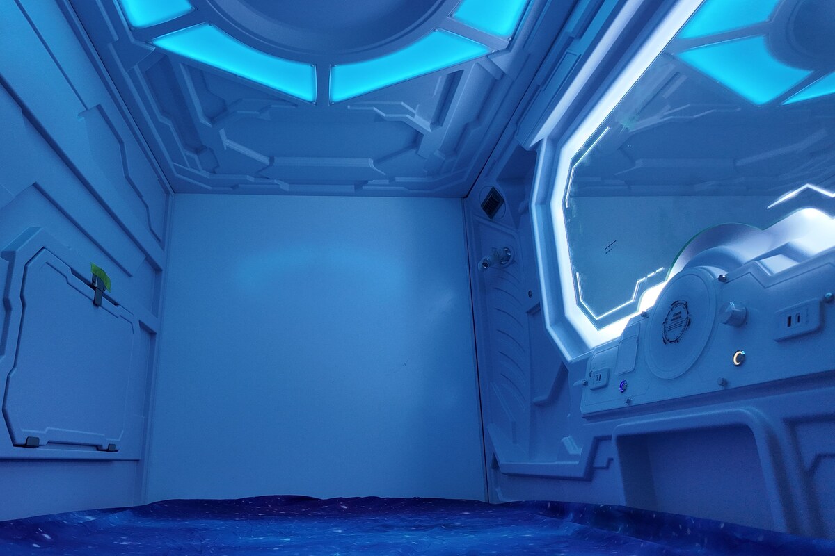Una habitación futurista con patrones geométricos y un panel de control central.