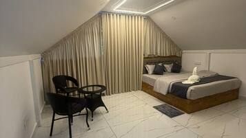 Un dormitorio con una cama, una silla, una mesa y una cortina.