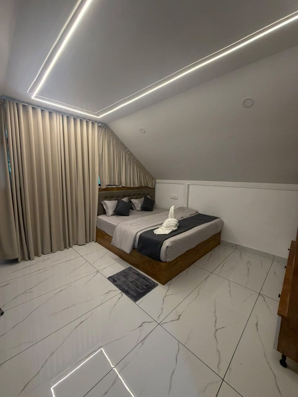 A modern bedroom with a bed, curtains, and a ceiling light.