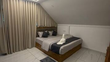 A modern bedroom with a bed, curtains, and a ceiling light.