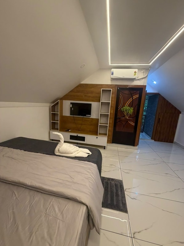 A modern bedroom with a bed, a TV, and a built-in shelf unit.