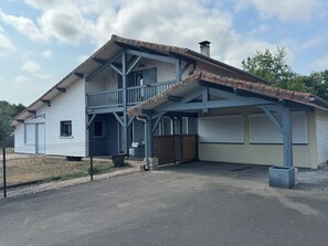 Ein zweigeschossiges Haus mit Balkon, Garage und umzäunter Garten.