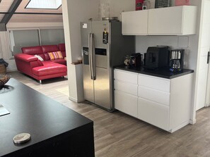 Eine kleine Küche mit einem Kühlschrank, einer Kaffeemaschine und einer Arbeitsfläche.