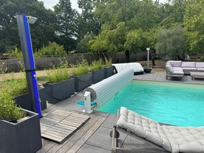 Ein Pool mit Holzterrasse, Liegestuhl und Grill.