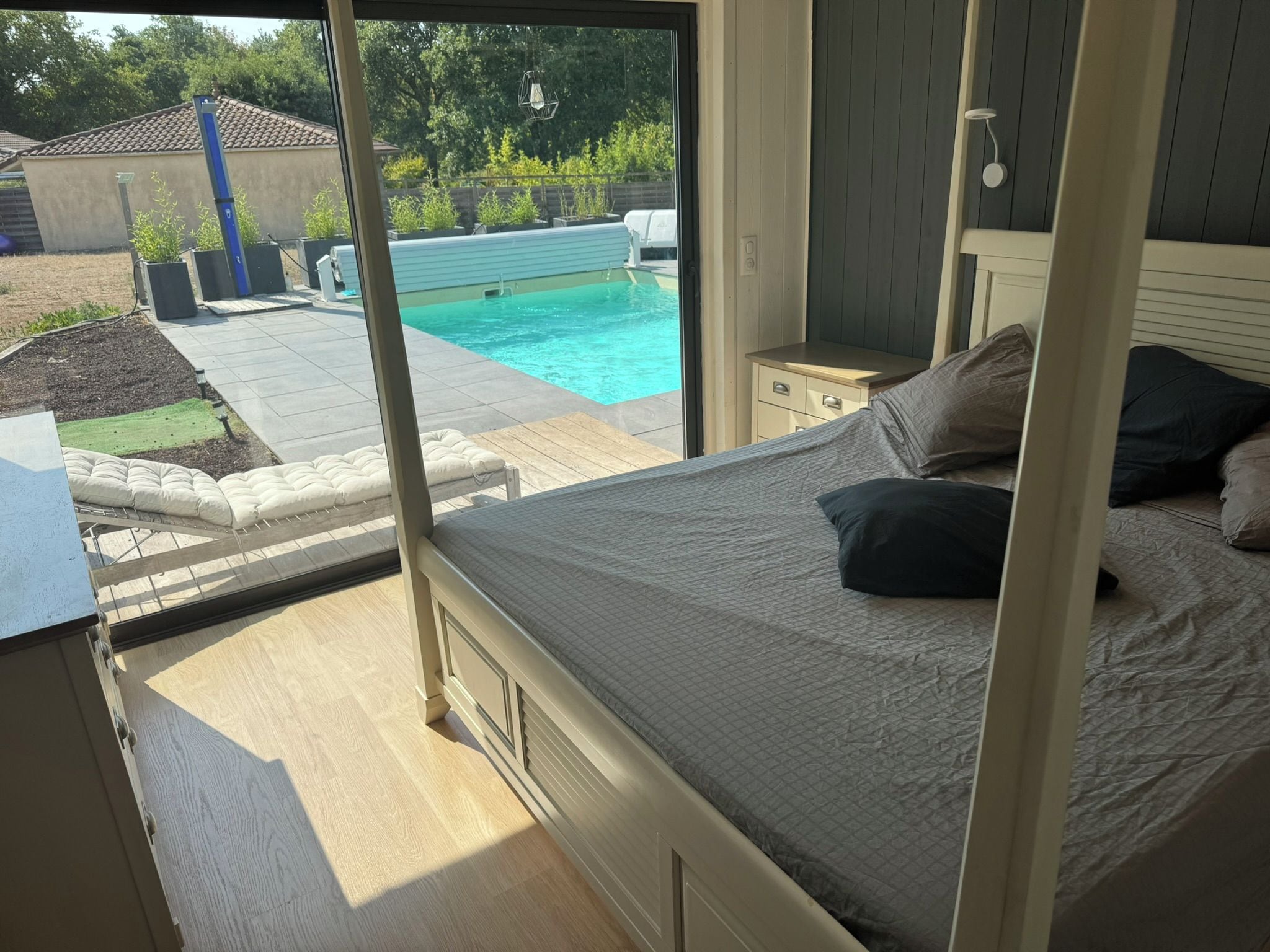 Un dormitorio con vista a una piscina, una terraza de madera y un jardín.