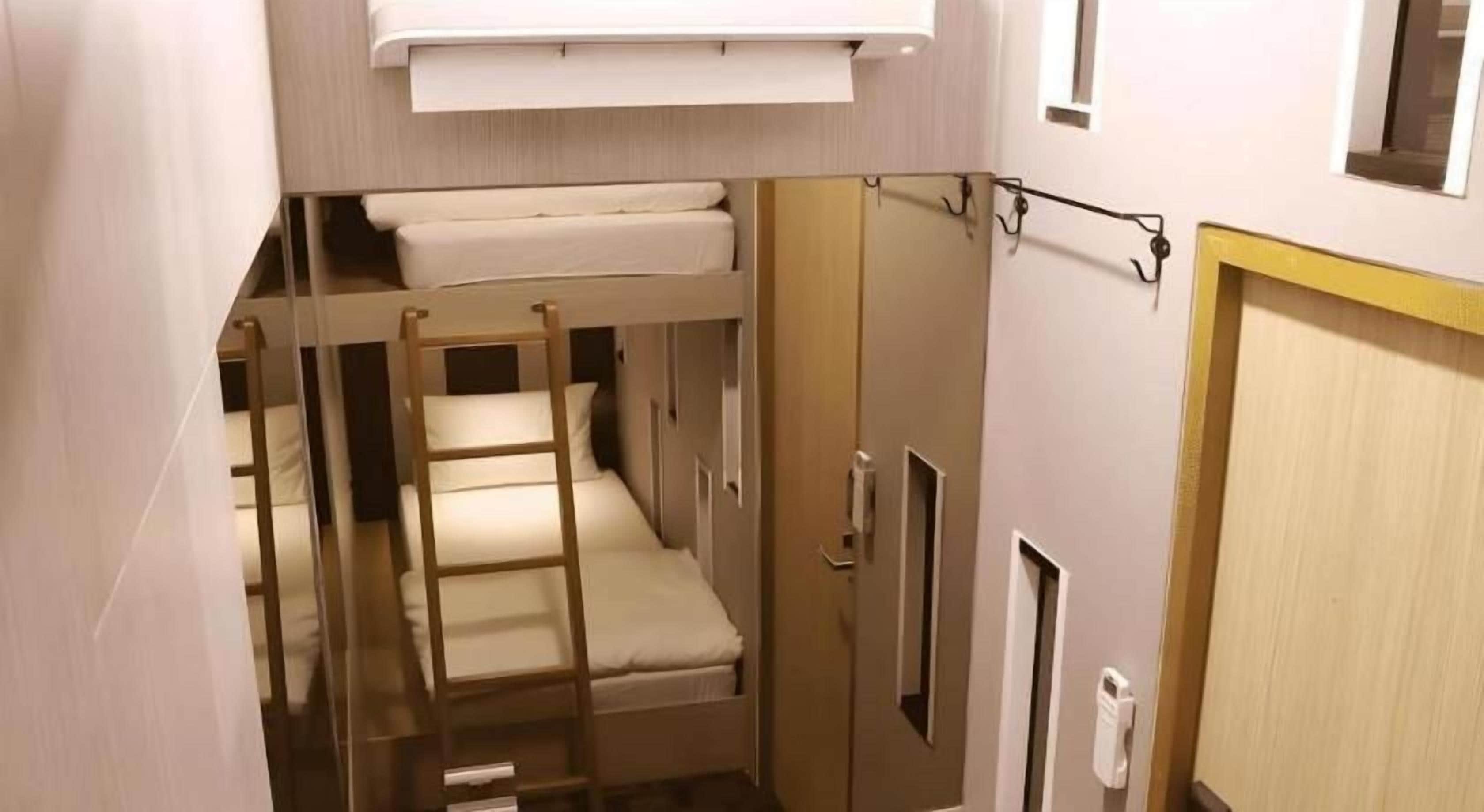 Ein Stockbett mit einer Leiter, einem Kleiderschrank und einer Tür.