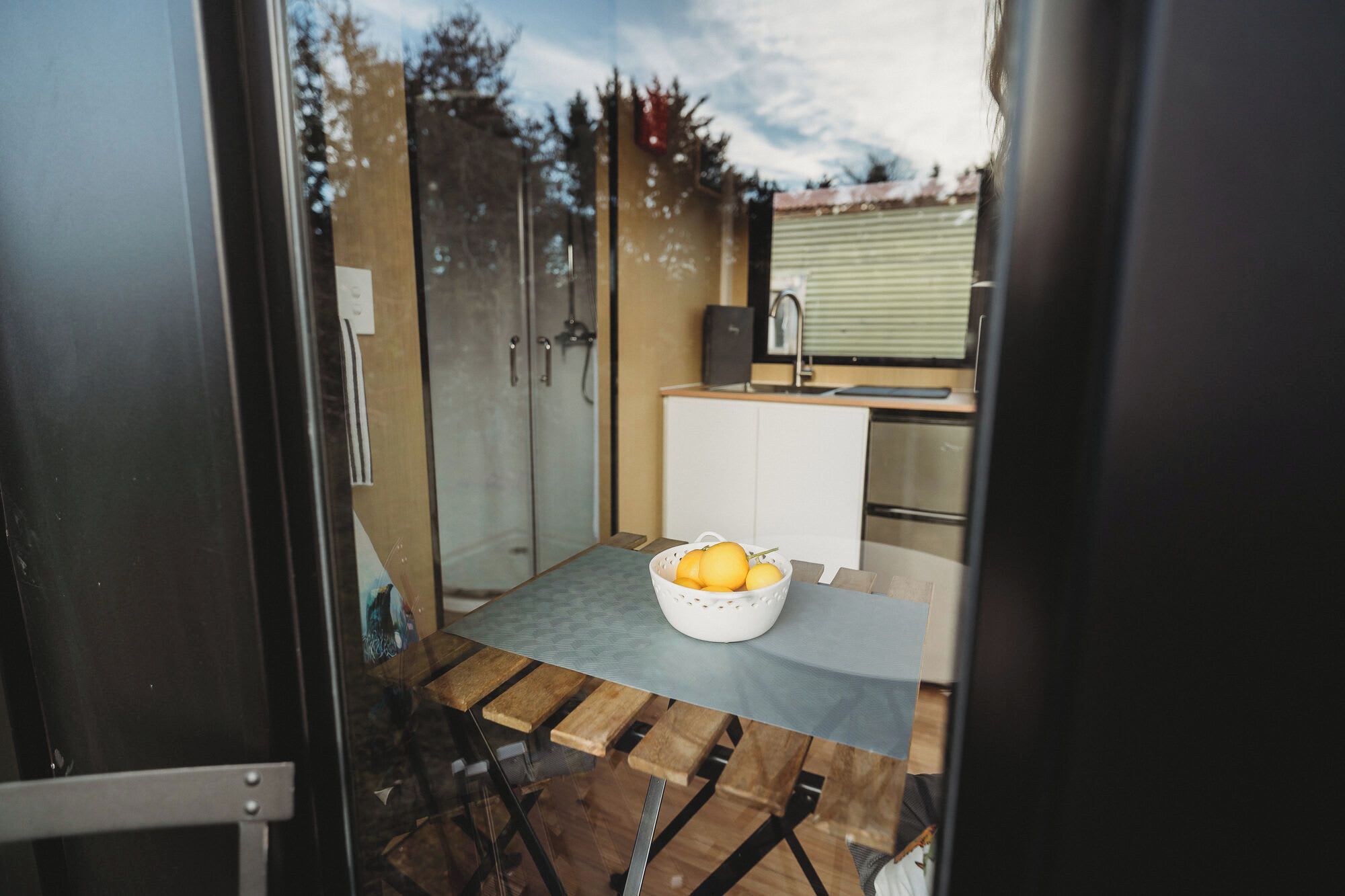 A compact kitchen with a sink, a small countertop, and a table with a fruit bowl.