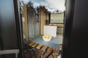 A compact kitchen with a sink, a small countertop, and a table with a fruit bowl.