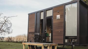 A modern cabin with a wooden exterior, a large sliding door, and a bench outside.