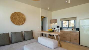 A modern living space with a sofa, a dining table, and a kitchen area.