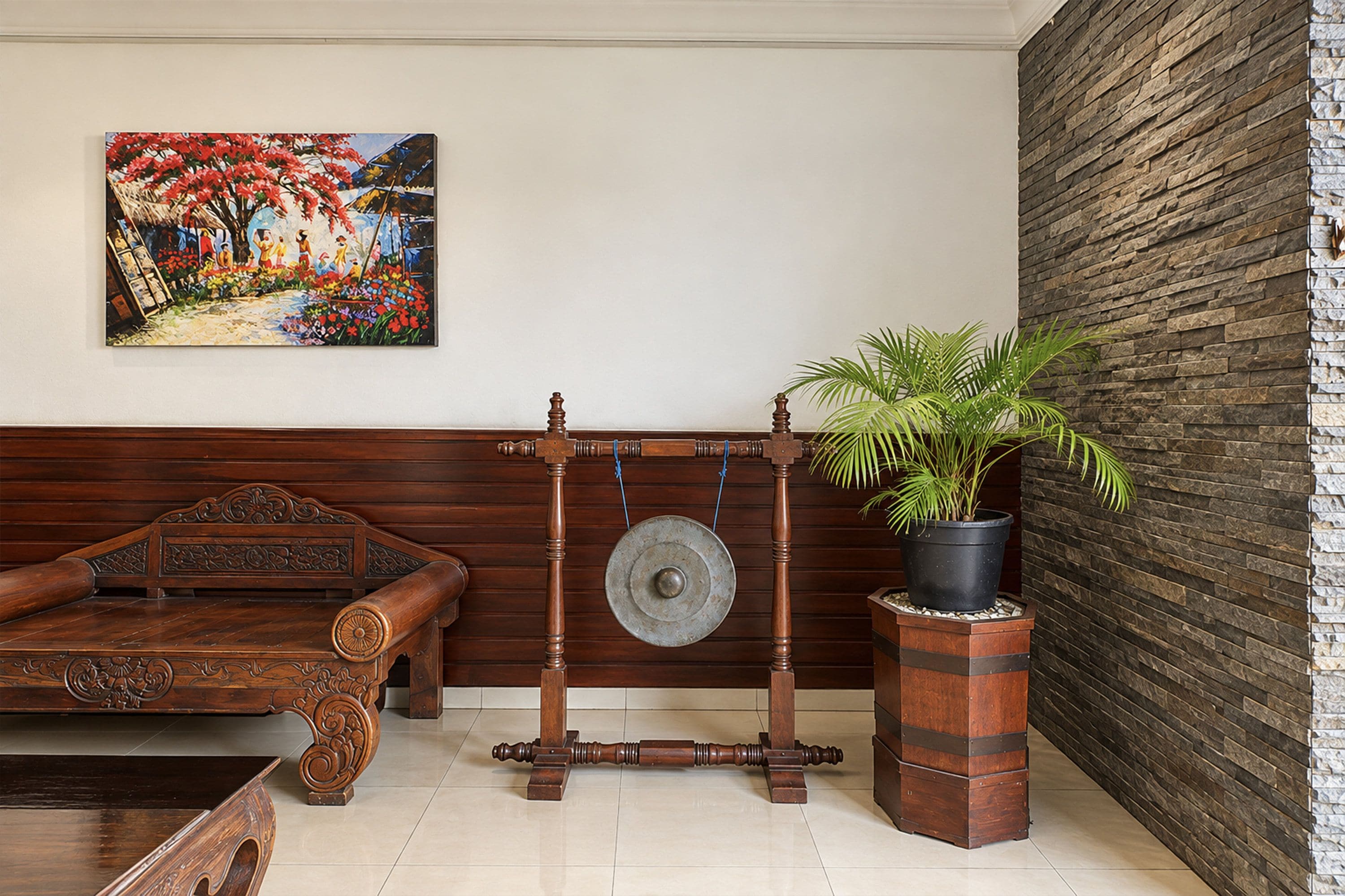 Una habitación con un sofá de madera, una mesa tradicional de madera con una campana colgante, una planta en maceta y un cuadro en la pared.