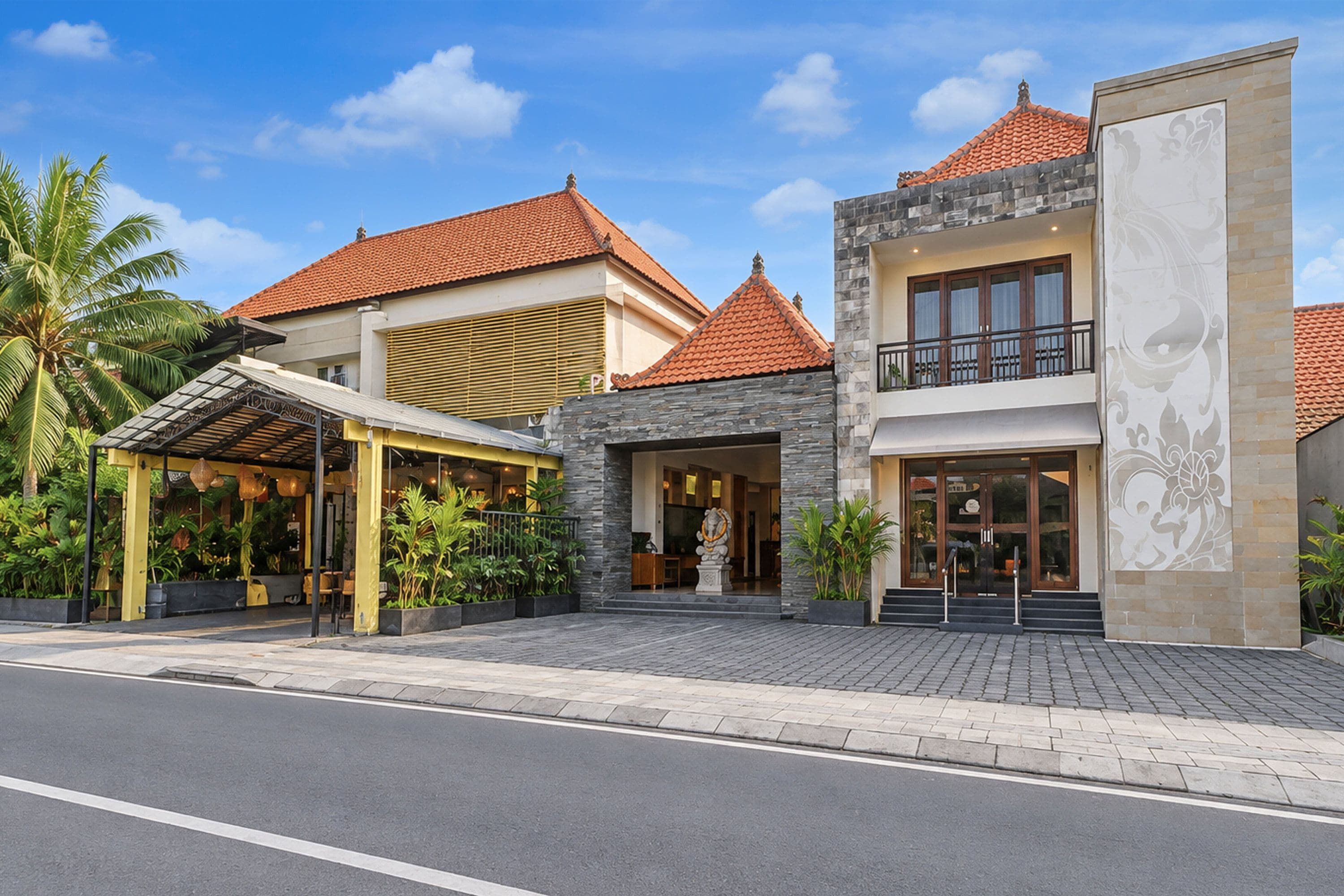 A hotel with a covered outdoor area, a stone facade, and a traditional tiled roof.