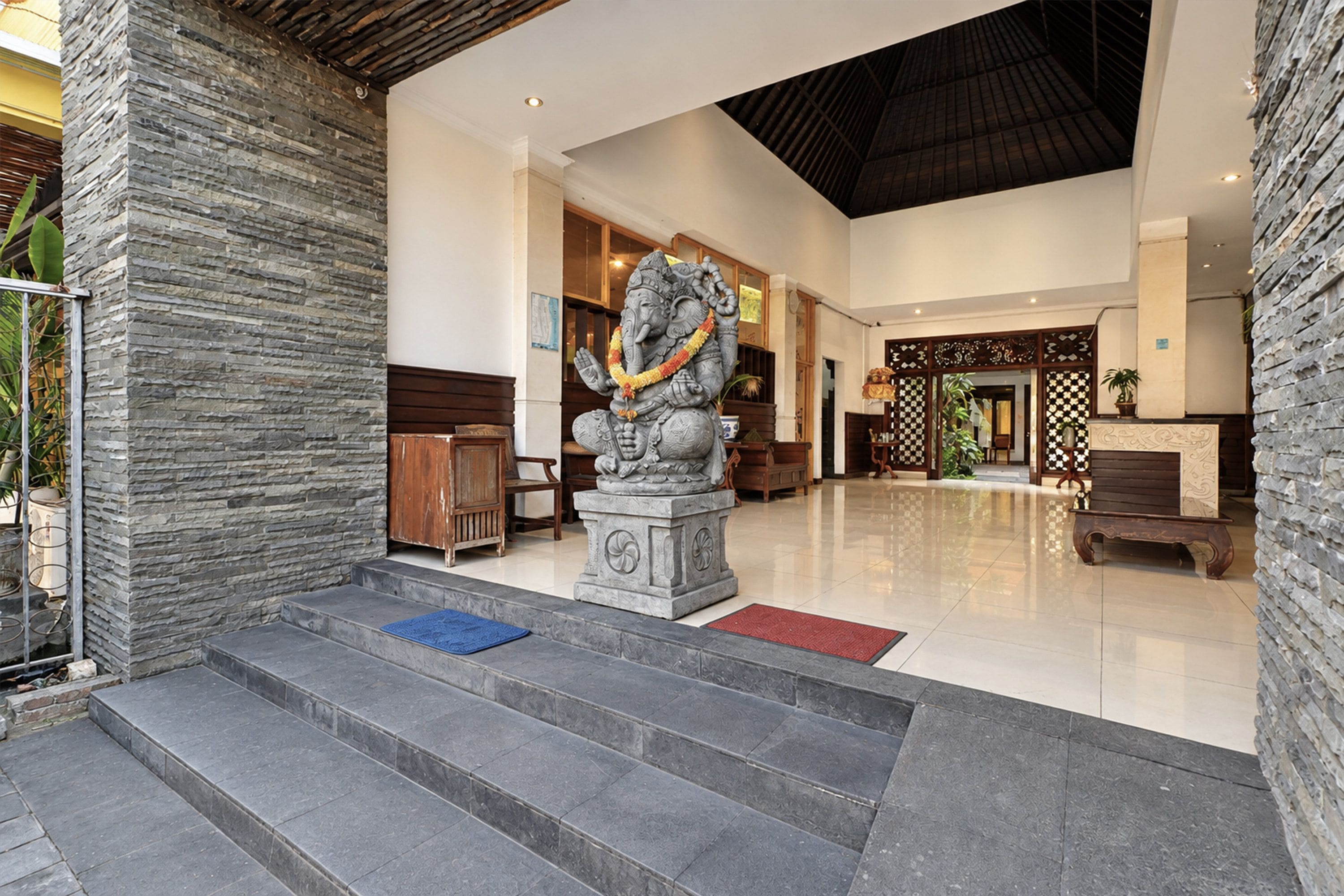 A reception area with a stone statue, a wooden reception desk, and a tiled floor.