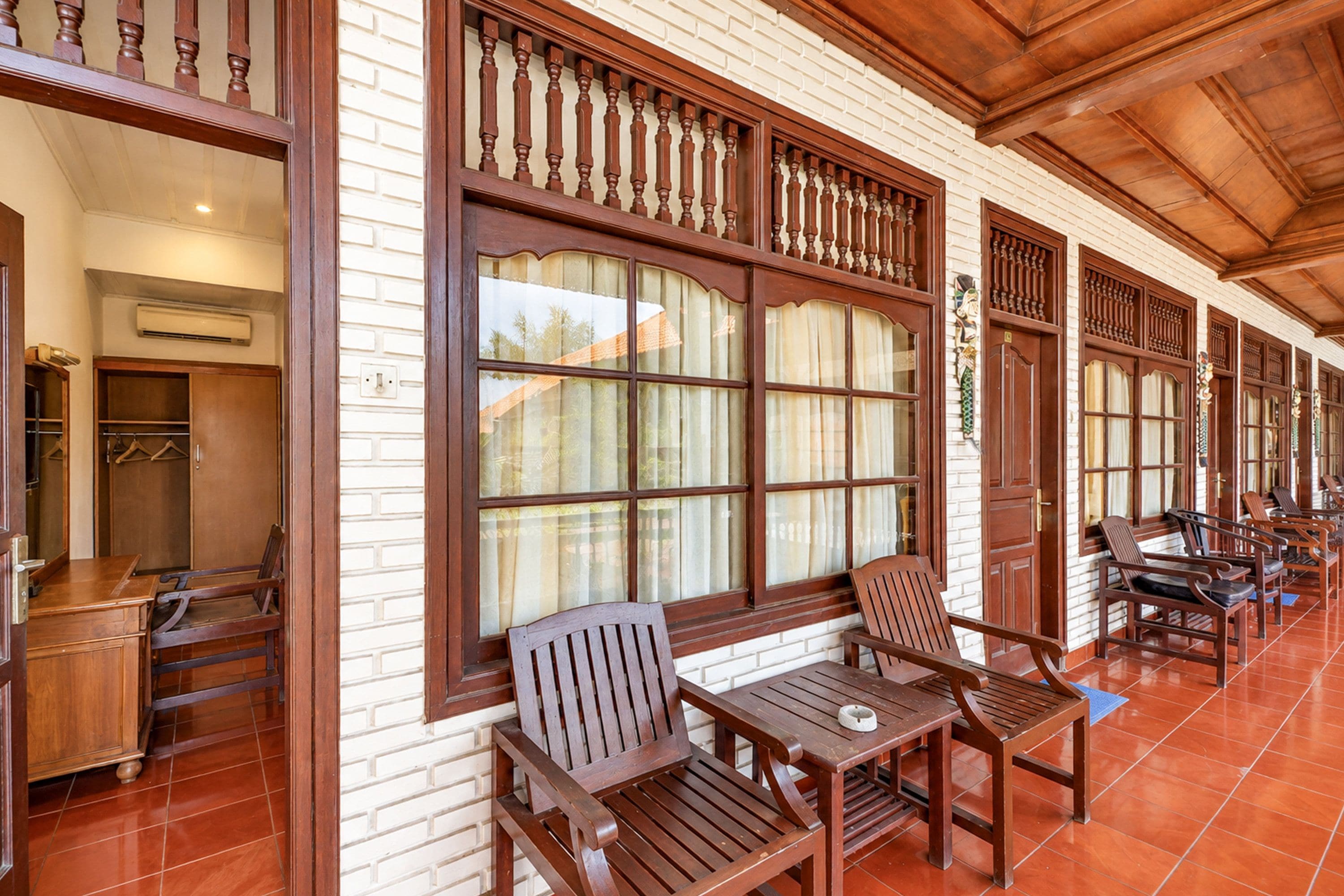 A corridor with wooden furniture and large windows with curtains.