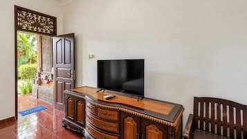 Una habitación con un armario de madera, un televisor de pantalla plana y una silla.