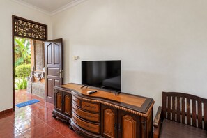 A room with a wooden cabinet, a flat-screen TV, and a chair.